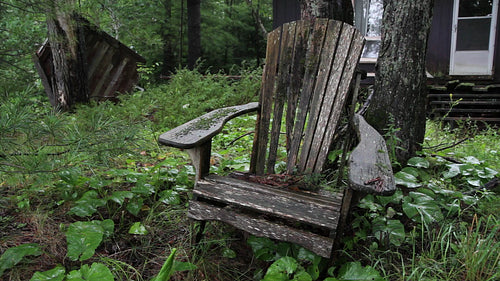 Wooden chair and abandoned cottage. Rain falling. HD video.