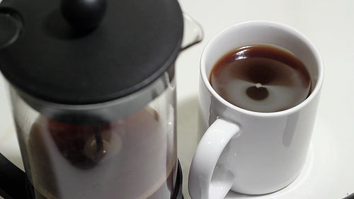 Fresh black coffee in focus with defocused french press. HD video.