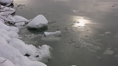 Snowy shore of winter river with drifting ice. HD video.