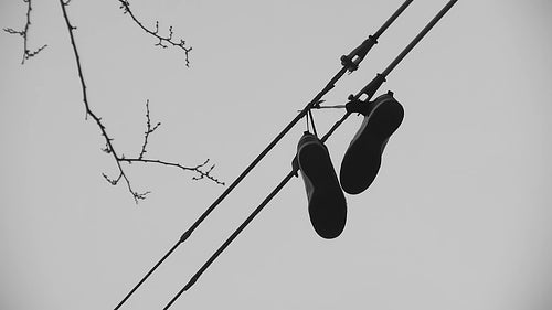 Sneakers hanging from wire. Black and white. HD video.