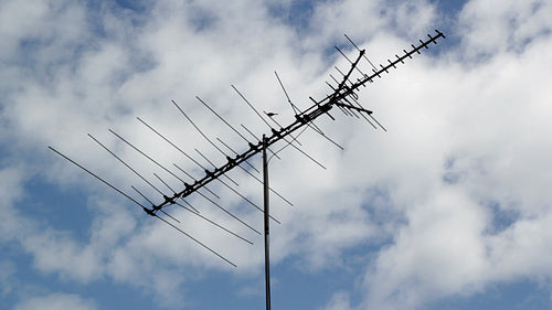 Vintage TV antenna with blue sky and puffy white clouds. Birds perching. HD video.
