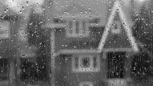 Rain on suburban window. Defocused house. Black and white. HD video.