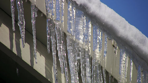 Frozen eavestrough with icicles. Detail of dripping water. HD video.