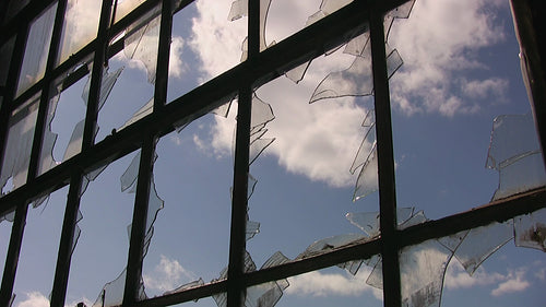 Broken window with shards of glass. Time lapse clouds move by in blue sky. HD video.
