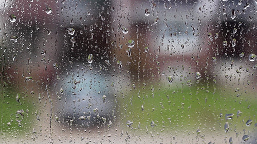 Rain on suburban window. Defocused house and car. Black and white. HD video.