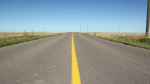 Low, center view of road with yellow line. Saskatchewan, Canada. HD.