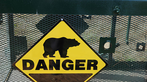 Yellow danger sign on outside of large bear trap. 4K.