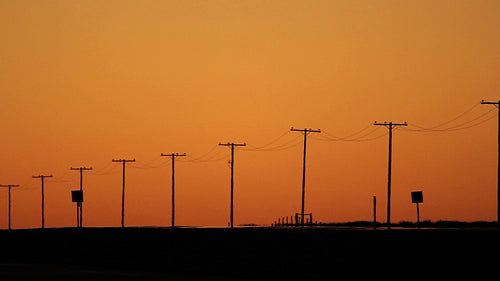 Telephone poles at dusk with orange sky. Saskatchewan, Canada. HD.