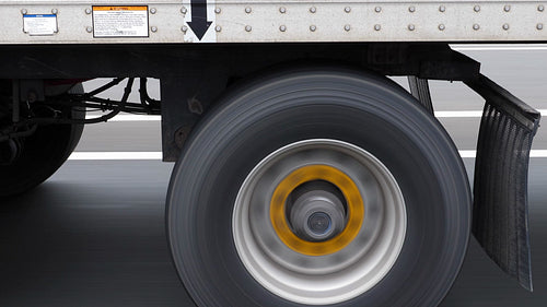 Passing commercial truck or lorry. Detail of wheels with yellow hubs. HD.