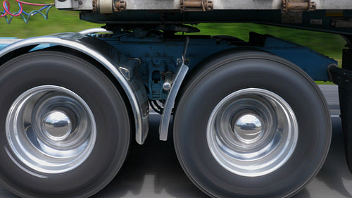 Driving beside tractor trailer. Detail of chrome wheels and trailer hitch. 4K.