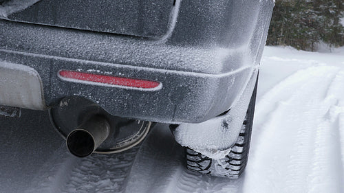 Winter SUV. Detail of snowy bumper & winter tires. Snow falling. Canada.