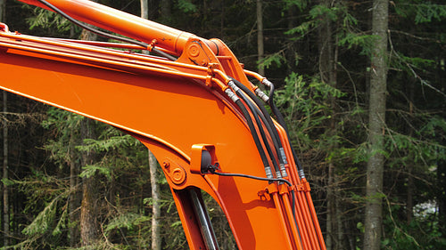 Detail of orange excavator with forest background. Ontario, Canada. 4K.