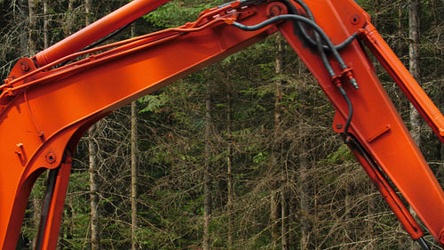 Detail of orange excavator swinging around. Clearing land in forest. 4K.