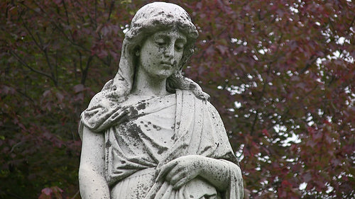 Grieving cemetery statue. Mournful figure looks downward. HD video.