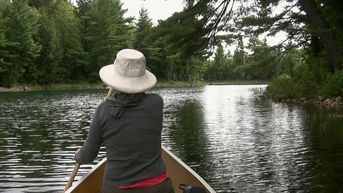 Woman paddles canoe. POV from stern. HDV footage. HD.