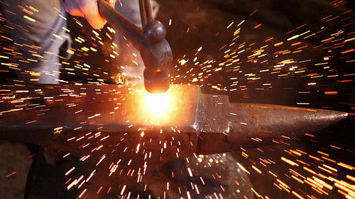 Blacksmith shaping a hot piece of metal on the anvil. Sparks in slow motion. HD.