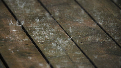 Rain falling on wooden deck. Shallow depth of field. Half-speed 4K clip. 4K.