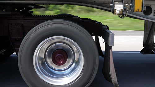 Driving beside tractor trailer. Detail of burgundy wheels and trailer hitch. 4K.