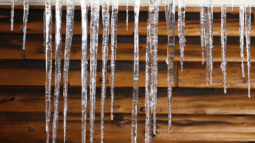 Dripping winter icicles with wooden cottage wall. Rural Ontario, Canada. 4K.