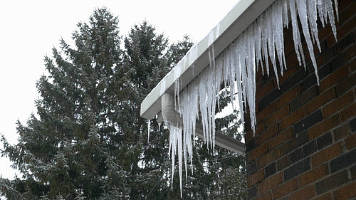 Slow motion snow falling. Icicles hanging from house. HD.