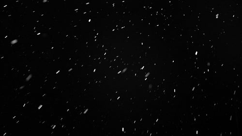 Falling snow and flakes illuminated underneath lights. Winter at night.