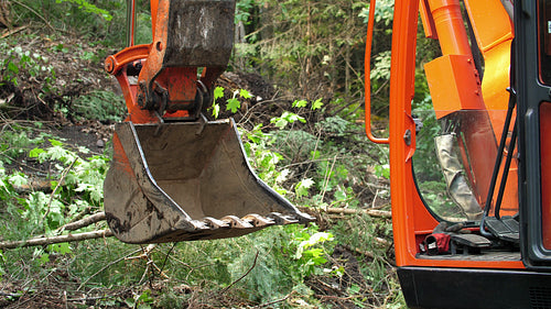 Detail of orange excavator bucket with forest background. Ontario, Canada. 4K.