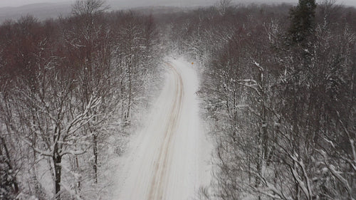 Drone following snowy rural road. Snow falling. 4K.