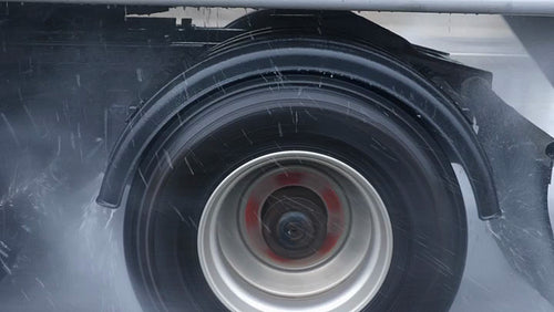 Passing truck on very rainy highway. Detail of wheel and water drops. 4K.