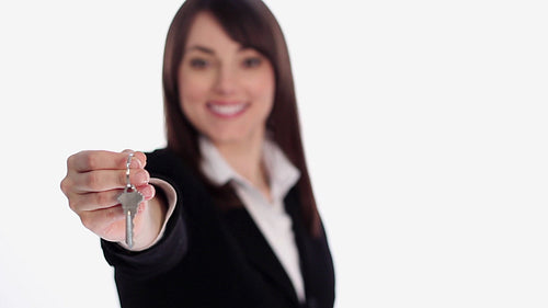 Attractive female realtor presents keys. Shallow depth of field. HD.