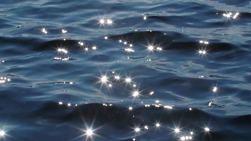 Slow motion blue lake water with brilliant sparkles from sun. HD.