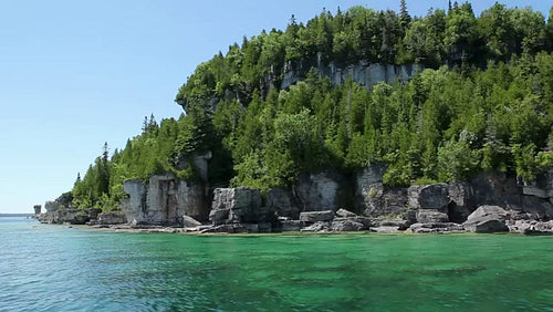Passing the cliffs and trees of Flowerpot Island in Tobermory, Ontario, Canada. HD.