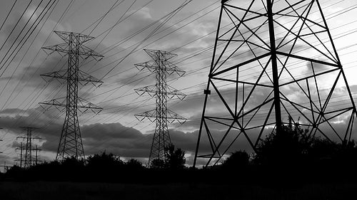 Hydro electric towers in silhouette at sunset. Toronto, Ontario, Canada. Black & white. HD.