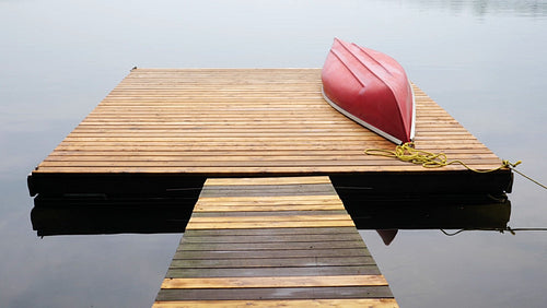 Red canoe overturned on wooden dock. Cottage country, Ontario, Canada. HD.