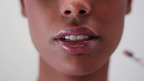 Lip gloss being applied to attractive young black woman. HD.