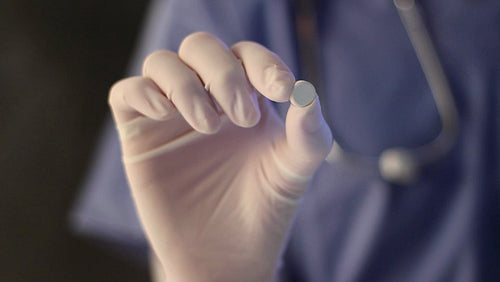 Closeup of nurse's hand holding up pill. Shallow depth of field. HD.