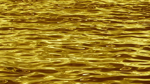 Slow motion metallic looking water. Silky smooth waves. Gold tint. HD.