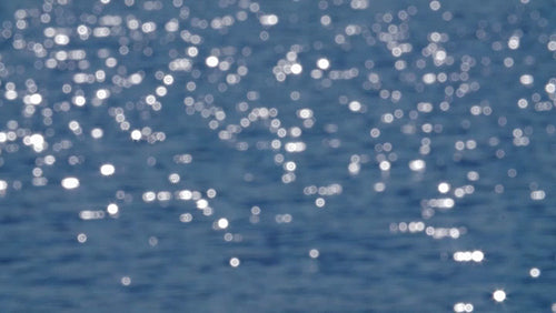 Sparkling, defocused blue lake surface in slow motion. HD.