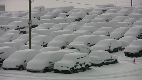 Snow covered vehicles in parking lot after snowstorm. HD video.