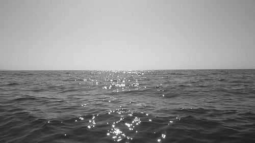 Slow motion sparkling lake water with copyspace. Mid level horizon. Black and white. HD video.