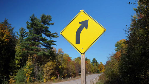 Yellow triangular road sign with corner in the distance. Autumn in Ontario. 4K.