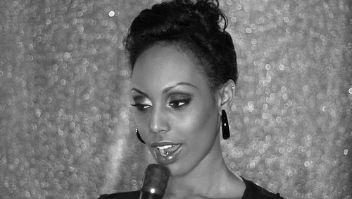 Attractive young black woman sings into a microphone. Black and white. Mellow. HD.