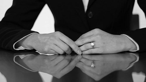 Closeup of caucasian woman's hands taking off wedding ring. Black and white. HD.