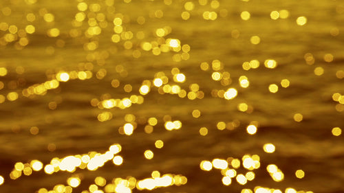 Slo mo defocused highlights on sunlit lake water. Golden tint. Lake Ontario. HD stock video.