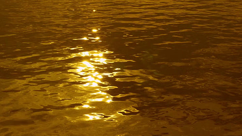 Slow motion lake with sun reflections. Tinted gold. HD.