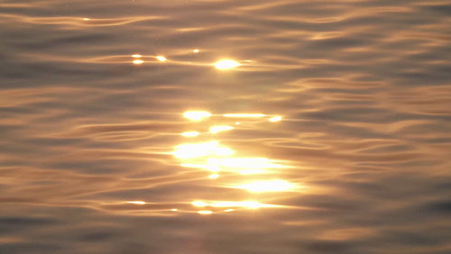 Slow motion sunset water. Beautiful texture with golden pink reflections. HD.