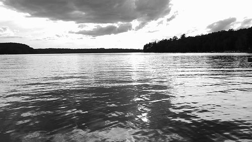 Slow motion lake and water w dramatic reflections of grey clouds at sunset. Black & white. HD.