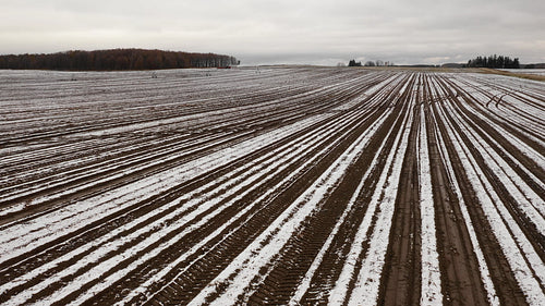 Slow drone flight over snowy farmers field in Ontario, Canada. 4K.