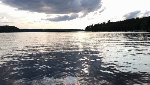 Slow motion lake and water w dramatic reflections of grey clouds at sunset. HD.