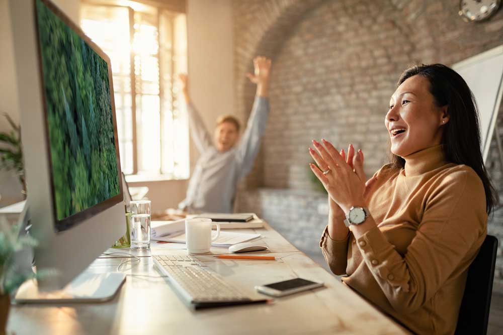 Photograph of happy asian woman and co-worker having found a stock footage clip on canada stock footage.com