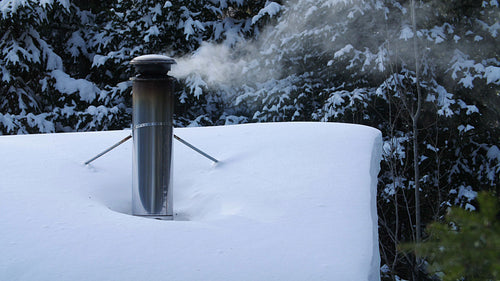 Winter chimney with wood smoke and snowy roof. Rural Ontario, Canada. 4K.